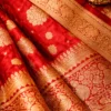 Close up of red Banarasi bridal saree fabric with gold zari weaving