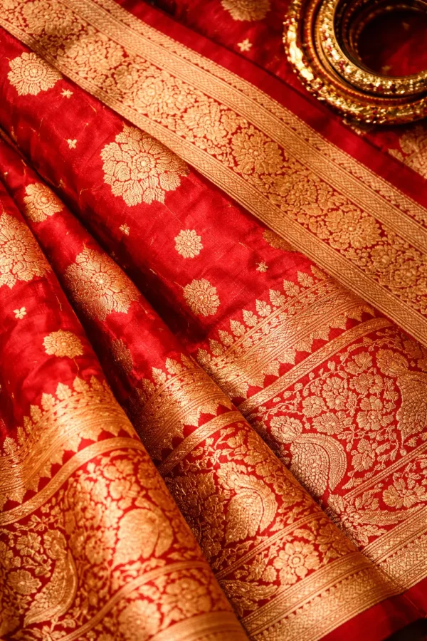 Close up of red Banarasi bridal saree fabric with gold zari weaving